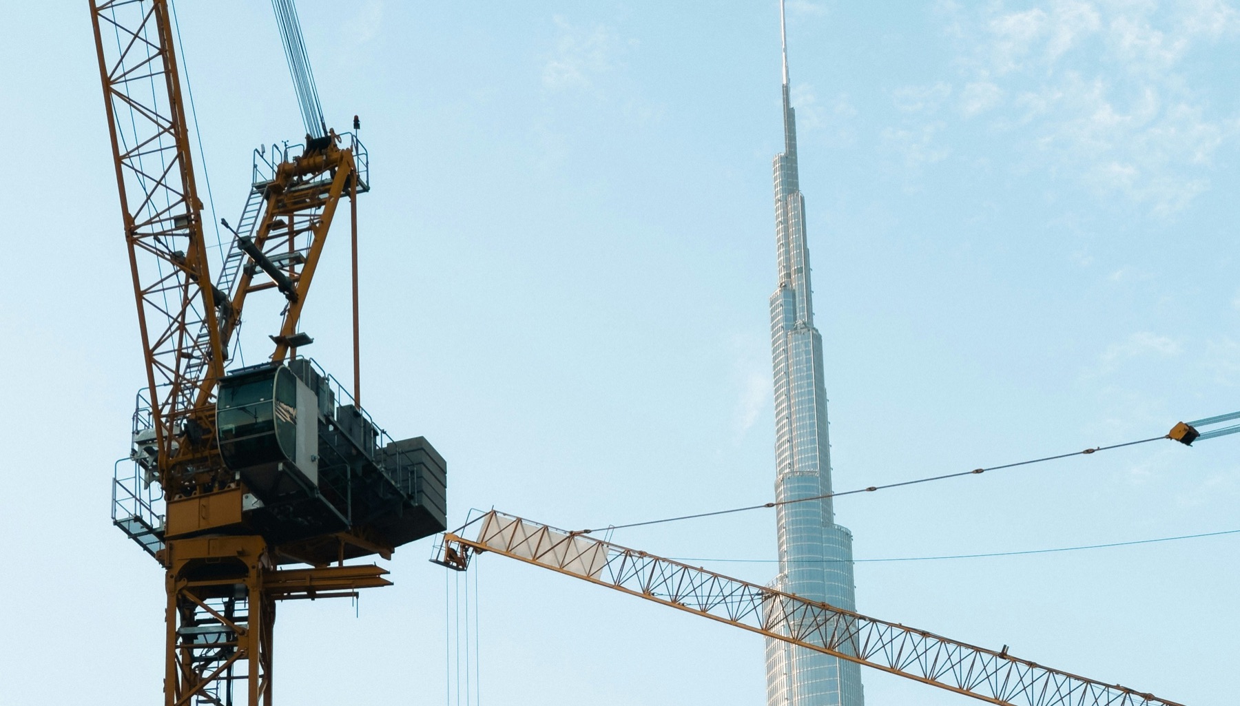 Construction cranes rising in front of the Burj Khalifa in Dubai